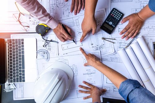 Hands pointing at architecture blueprints.